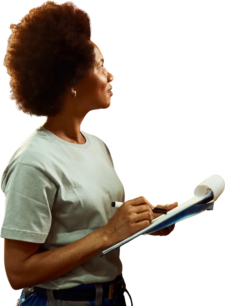 A warehouse worker writing an inventory list while checking stock.